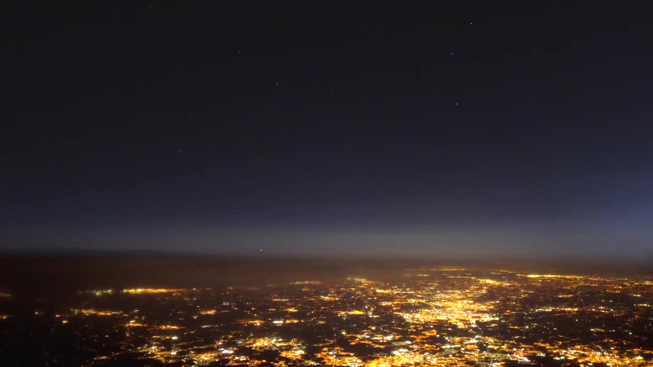 从飞机驾驶舱的夜景延时拍摄，地球上的灯光和上面的银河系