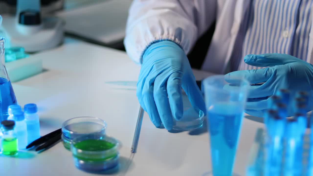 科学家们在玻璃测试盘上对琼脂进行生物学实验。博士科学家在实验室的烧杯上分析有色液体以分离DNA和分子。