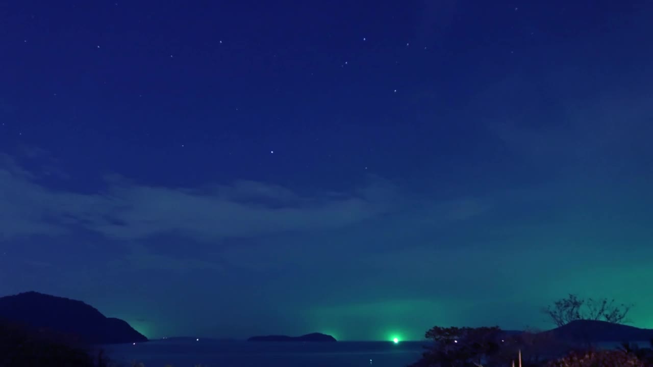 深蓝色的星空，明亮的绿色星光，热带夏季岛屿天堂，平静的海水和海浪