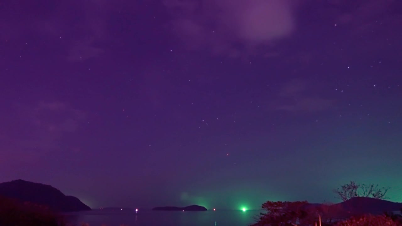 详情图-明亮的绿色星光在品红星空在平静的海浪和海水与剪影山岛在森林的夜空