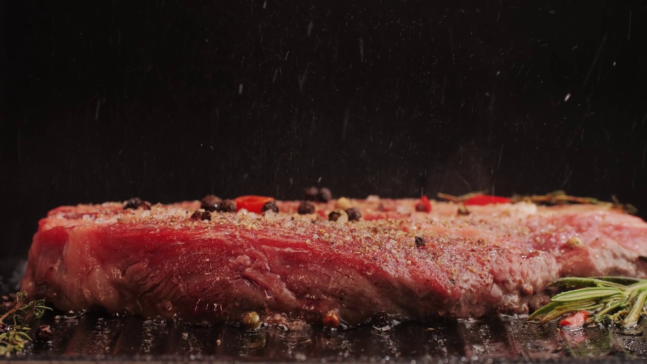 新鲜的大理石牛肉与胡椒，盐和迷迭香特写特写。在烤架上用油烹调多汁的牛排。优质有机和牛肉