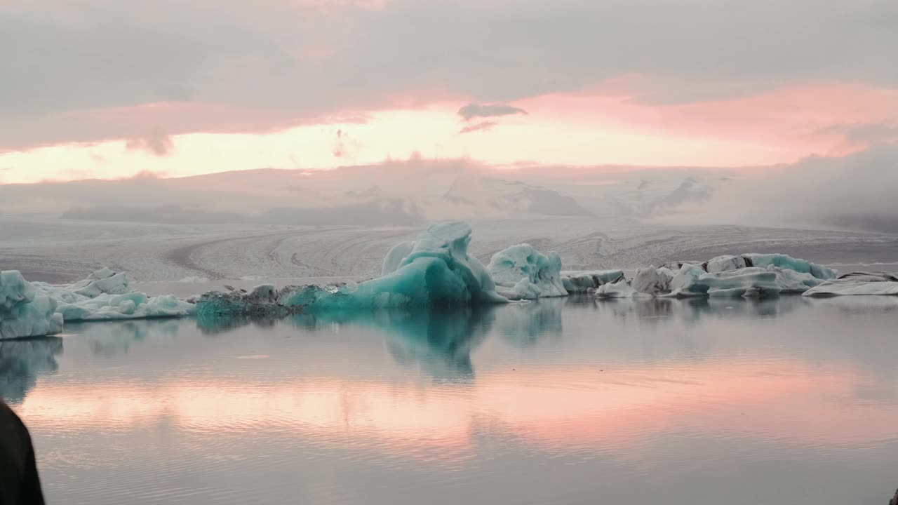 冰山游泳在Jokulsarlon，冰岛冰川泻湖在黄金时间日落，倒影在水中