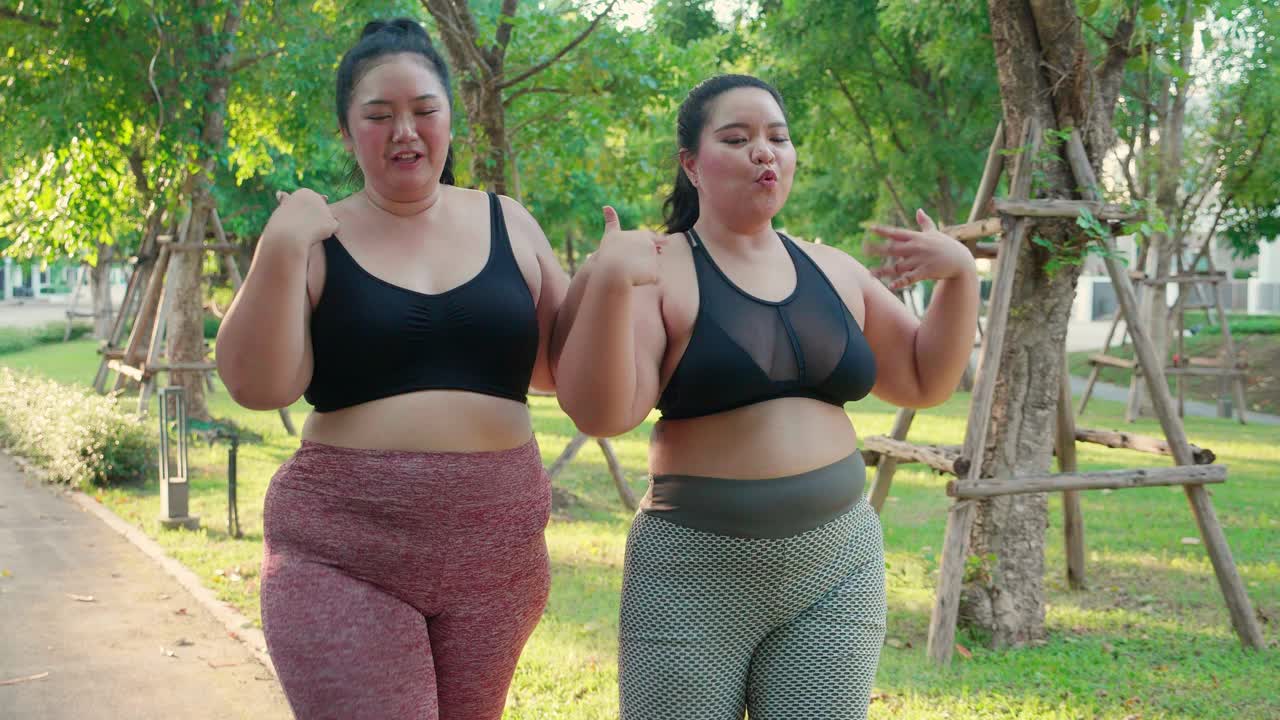 两个肥胖的亚洲女性穿着运动服在公园的小路上慢跑，肥胖的女性和朋友一起做有氧运动或散步，锻炼和锻炼，加上身材和健康减肥。