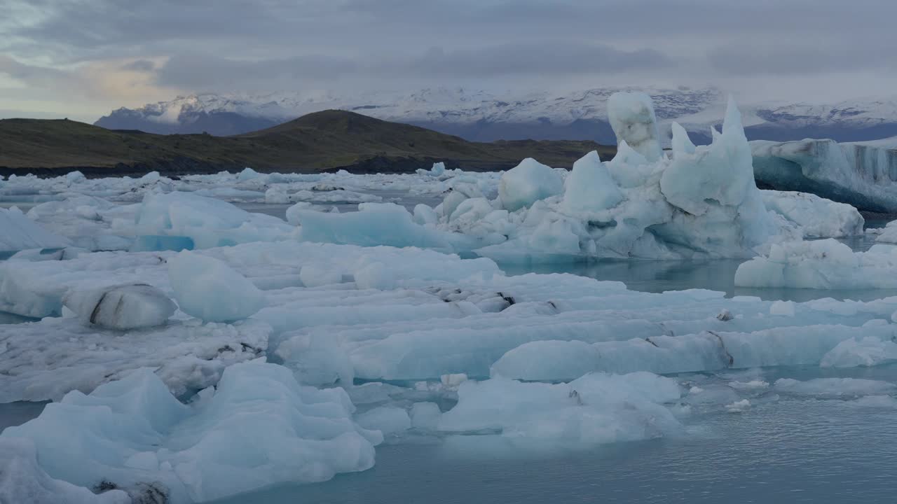 冰川泻湖，Jökulsárlón，冰岛，展示冰山在冰冷的蓝色的水和雪山为背景