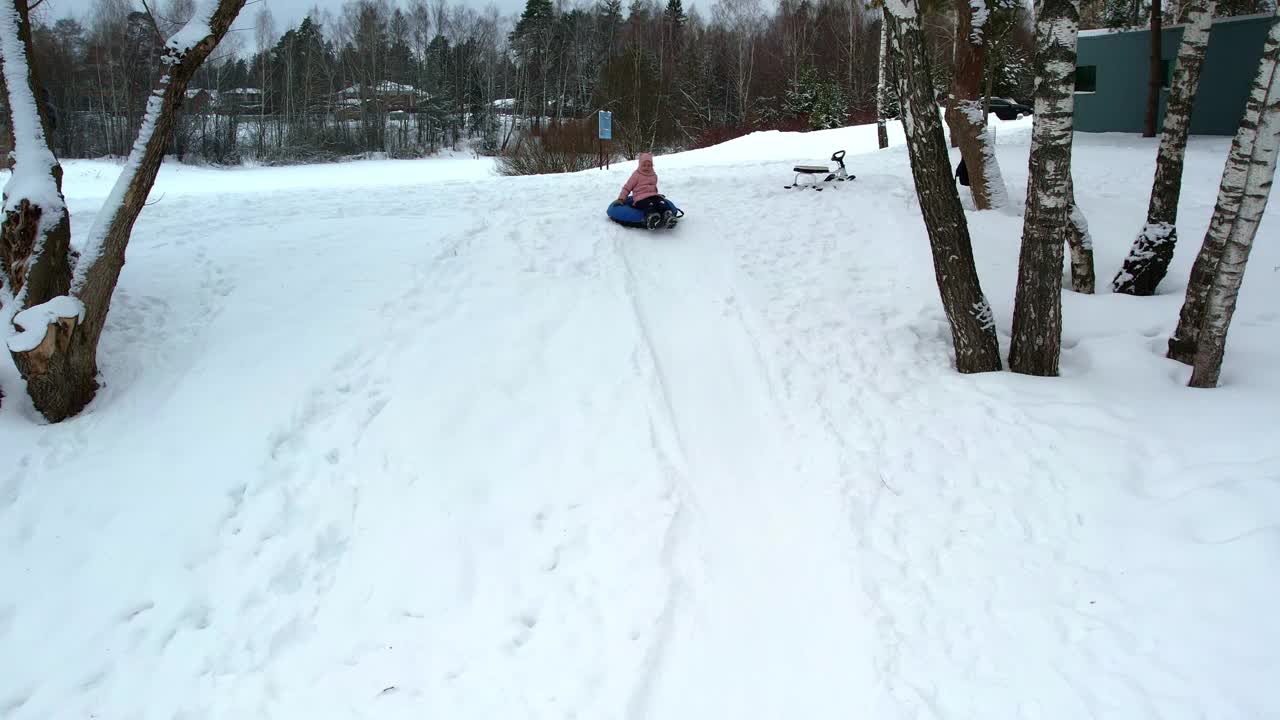 小孩子三胞胎姐妹在冬天骑在一个充气奶酪蛋糕与低雪坡