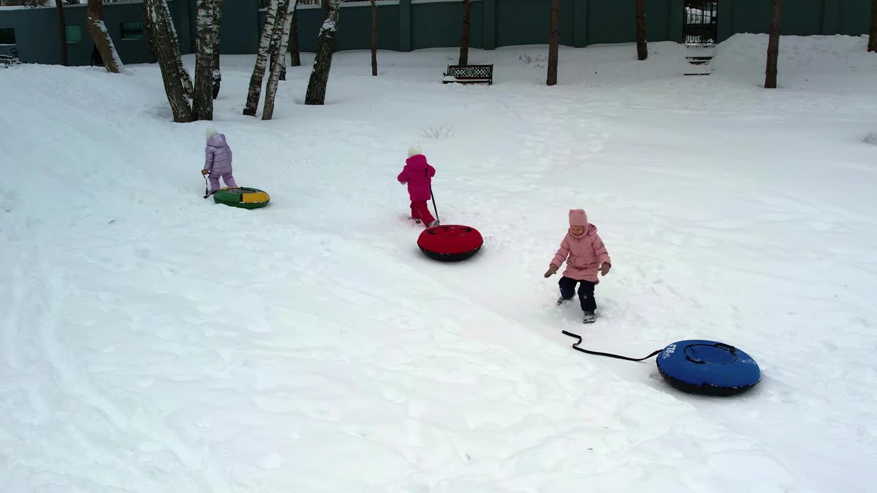 三胞胎小姐妹在冬天拿着充气芝士蛋糕爬雪山