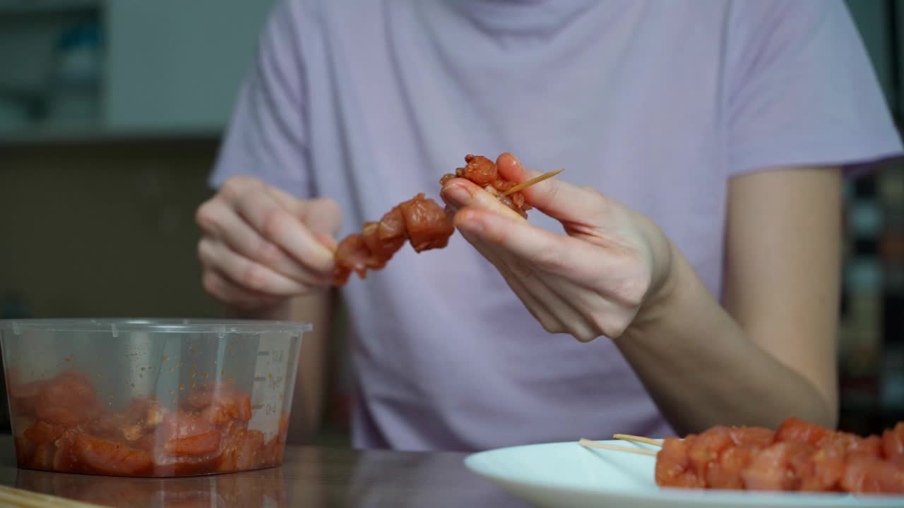 家庭主妇在厨房里用木串准备羊肉串。