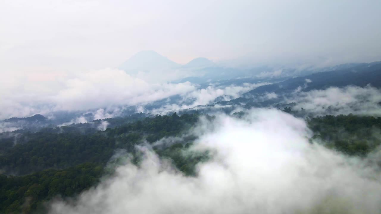 在充满活力的热带雨林上空的航拍镜头，背景是一座活火山，突出了保护工作，航拍4k无人机镜头