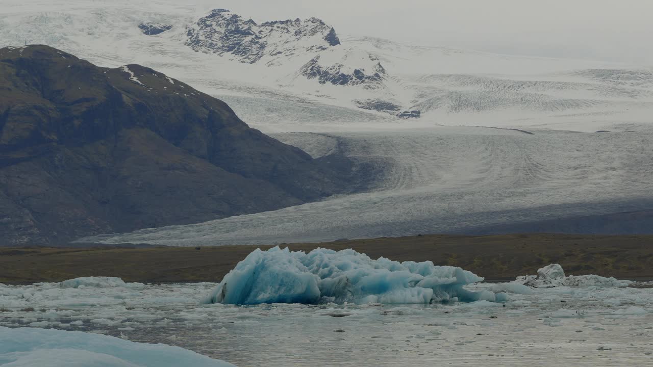 冰岛Jökulsárlón的冰川泻湖，冰川漂浮在冰冷的水中，背景是雪山