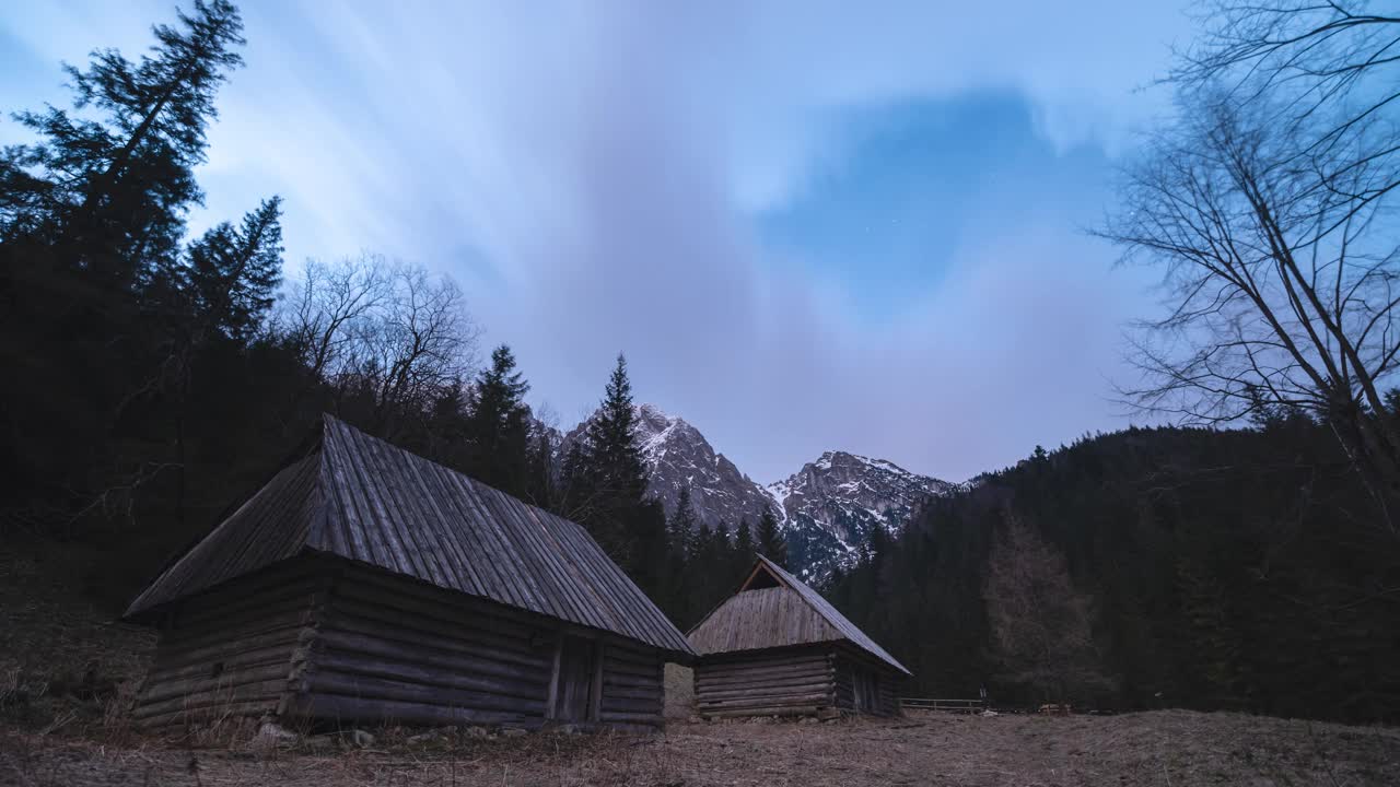 春夜的山景，有时可以看到云层后面的星星。前景是几座木屋