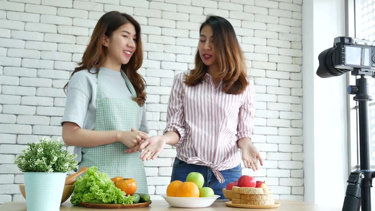詳情圖-亞洲網(wǎng)紅視頻博主直播健康飲食生活方式。兩個(gè)年輕的女性朋友博主vlog快樂(lè)的生活方式如何吃蔬菜，水果，素食產(chǎn)品。兩個(gè)女人在談?wù)撋缃幻襟w視頻