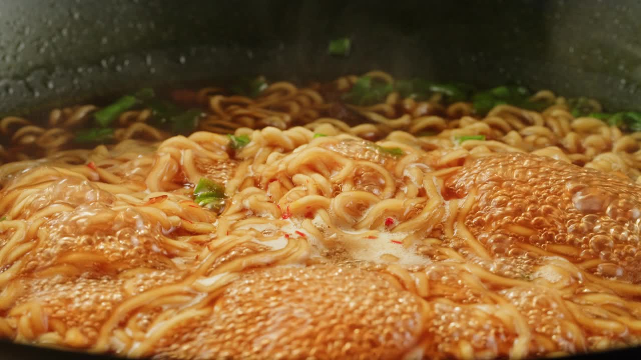 沸水煮泡面加香料特写。亚洲快餐。方便面，即方便面，是一种由预先煮熟并干燥的面条和调味粉和调味油组成的食品。烹饪或浸泡