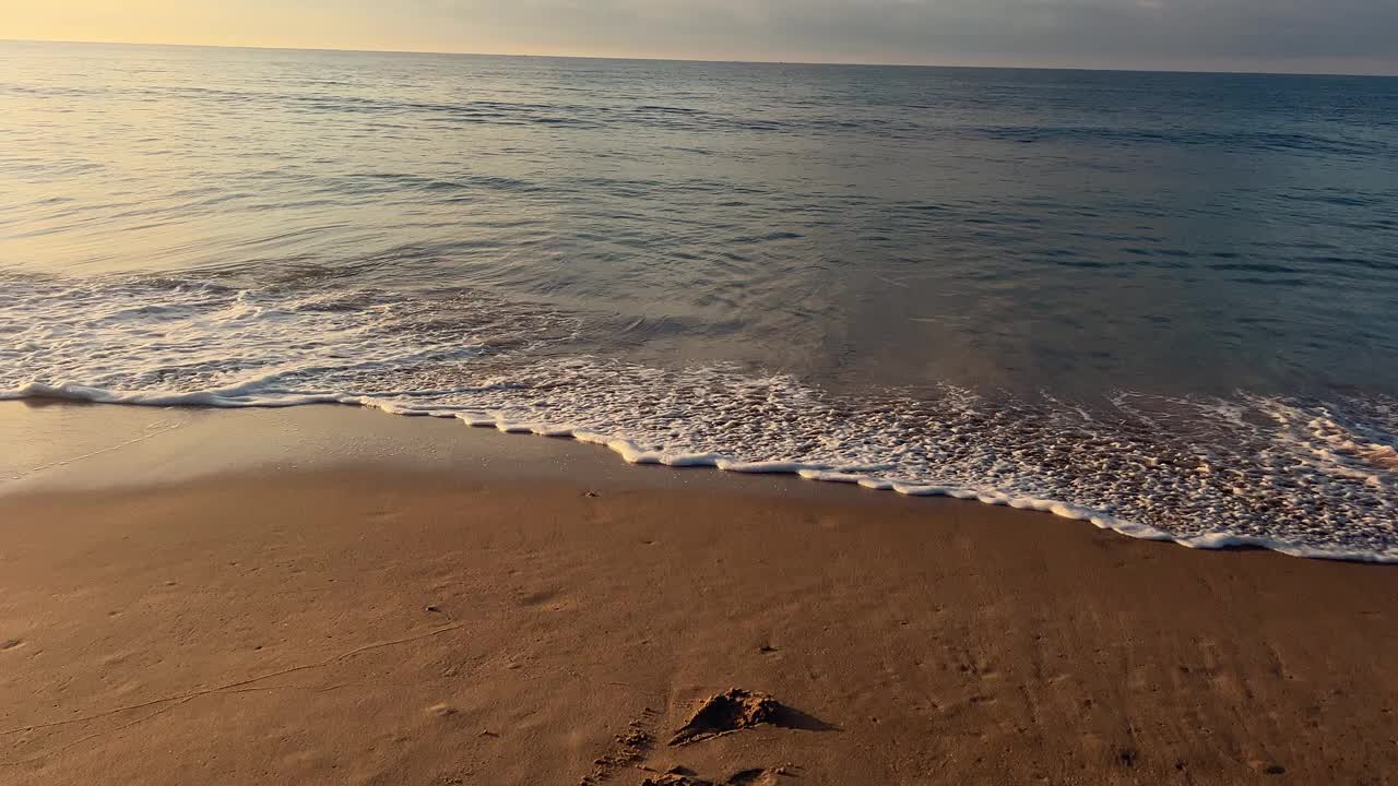 漫步在海边，温柔的海浪抚摸着沙滩，混凝土立方体依偎在沙滩上，以防止侵蚀。位于西班牙。