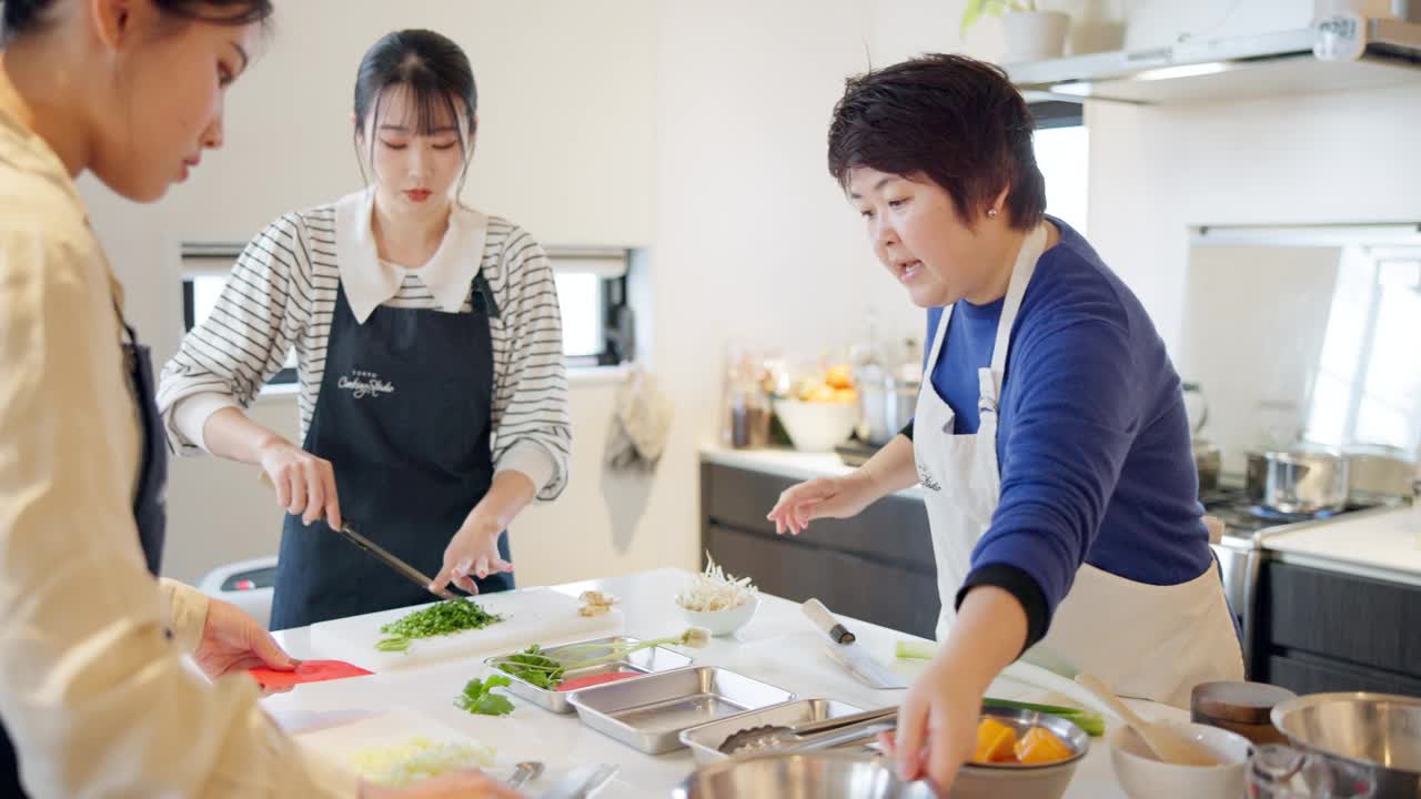 妇女，厨师和烹饪传统或日本食品教学，课堂或学习。女同学和厨房指导准备拉面碗，供营养、旅游或当地体验