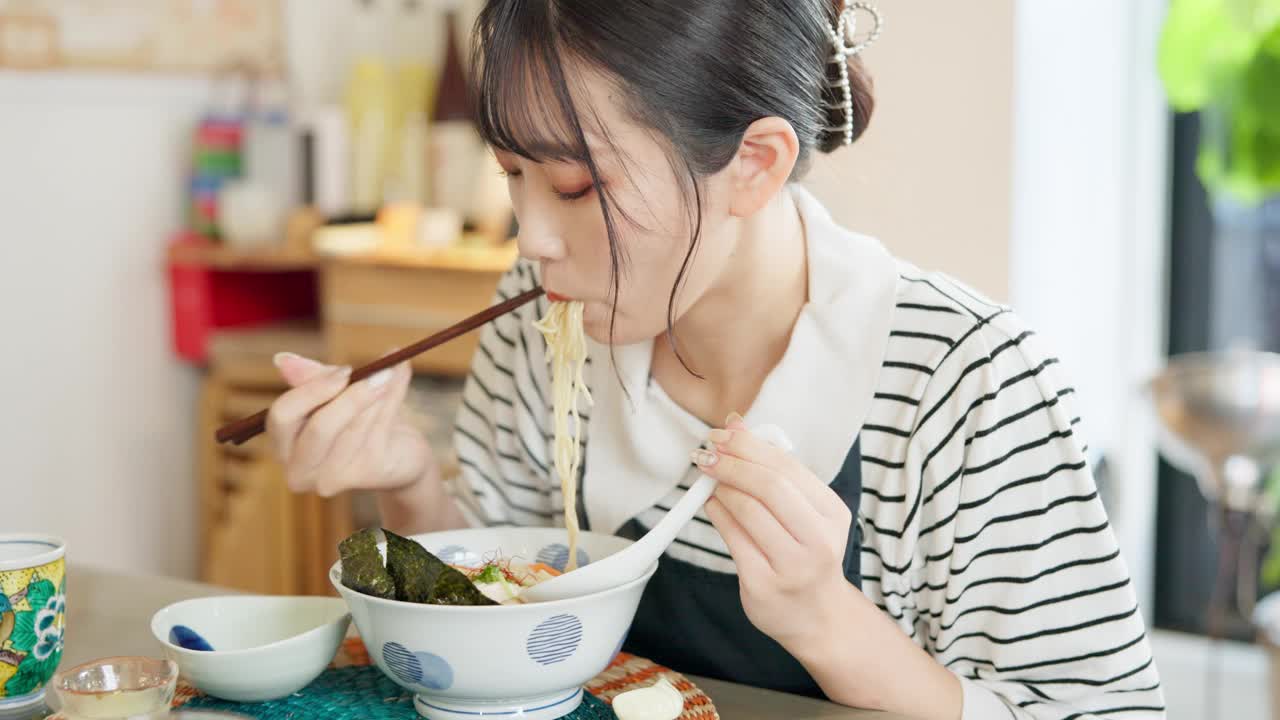 日本妇女在餐馆，吃拉面和食物的午餐或晚餐。面、碗和一个饥饿的年轻人、顾客或女孩用筷子独自享受健康餐或传统美食