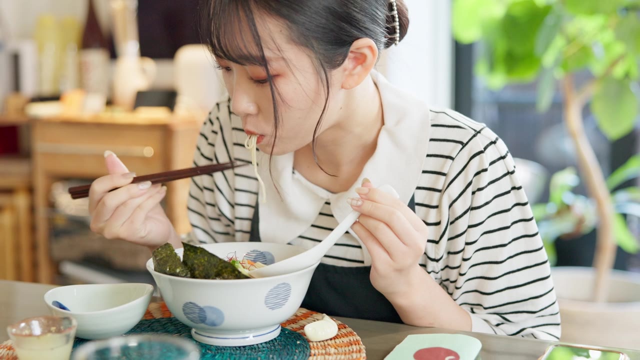 详情图-日本妇女在餐馆，吃拉面和食物的午餐或晚餐。面、碗和一个饥饿的年轻人、顾客或女孩用筷子独自享受健康餐或传统美食