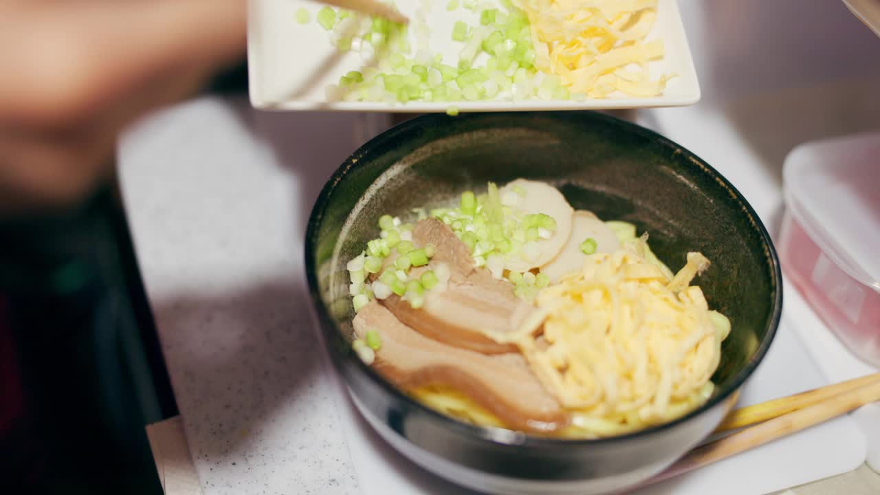 日本料理、拉面和餐厅里的菜用葱和食材、筷子和厨师的技巧配合装饰。烹饪传统菜肴的人，特写与营养和装饰在面条上