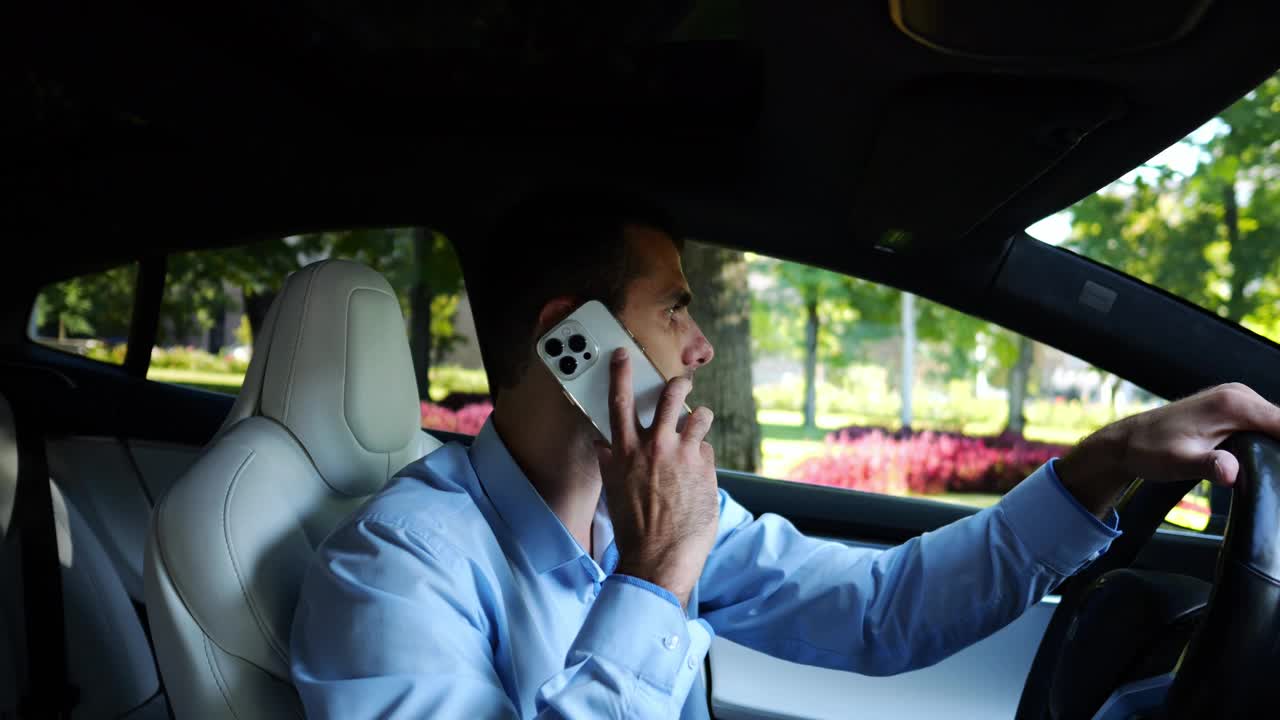 自信的商人在城市道路上开着电动车，一边打电话。男性商人在城市里开着电动汽车，用智能手机说话。商业概念。