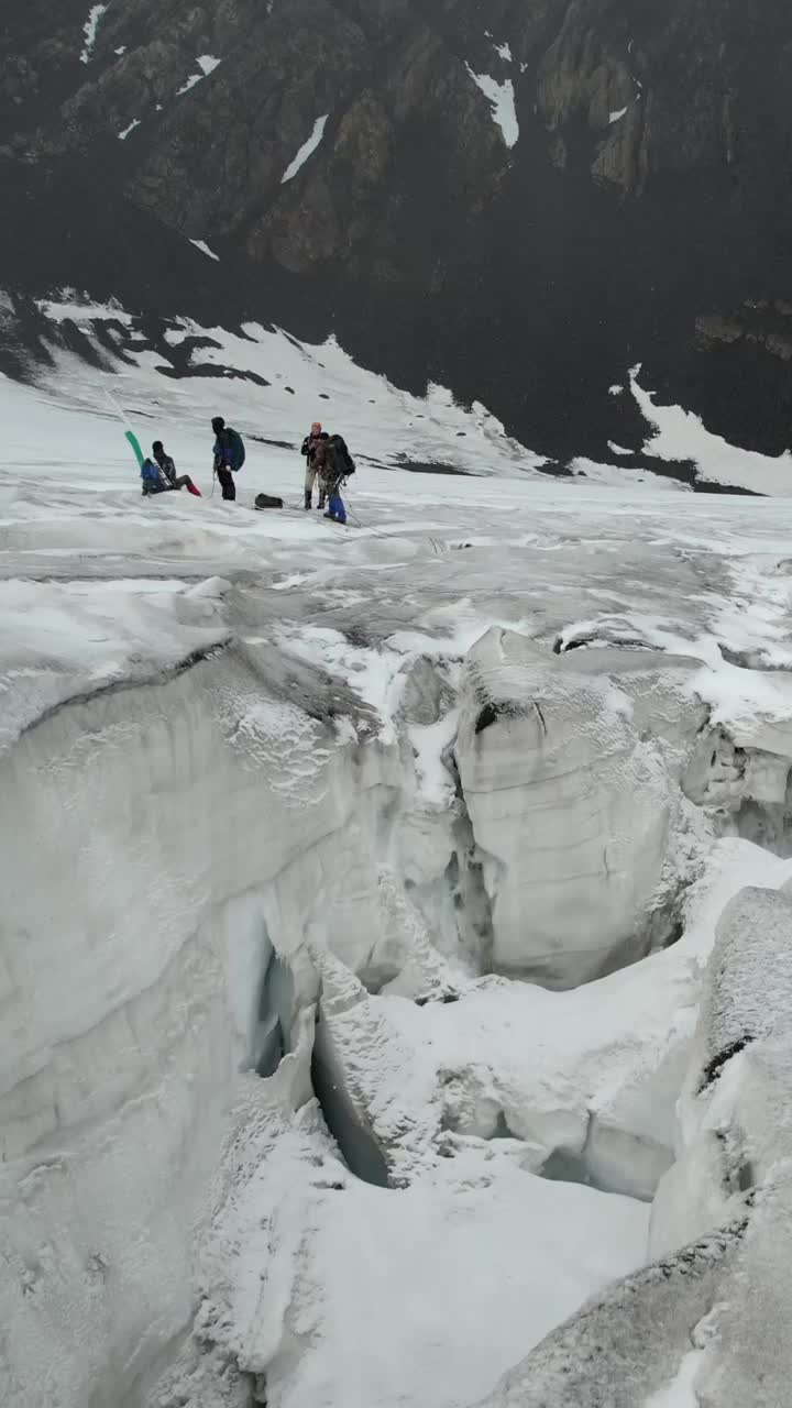 登山者在冰川上行走。无人机的垂直视频。