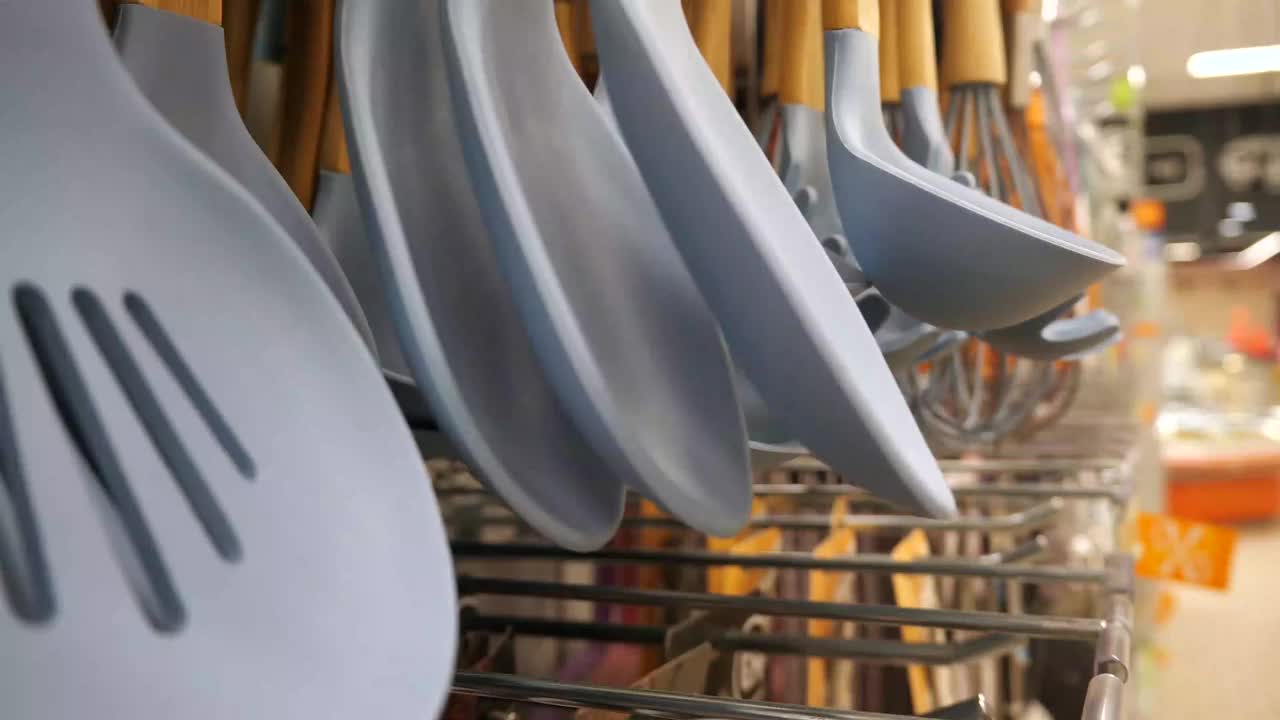 客户选择厨具。顾客的手触摸了店内的厨具，拿了一个