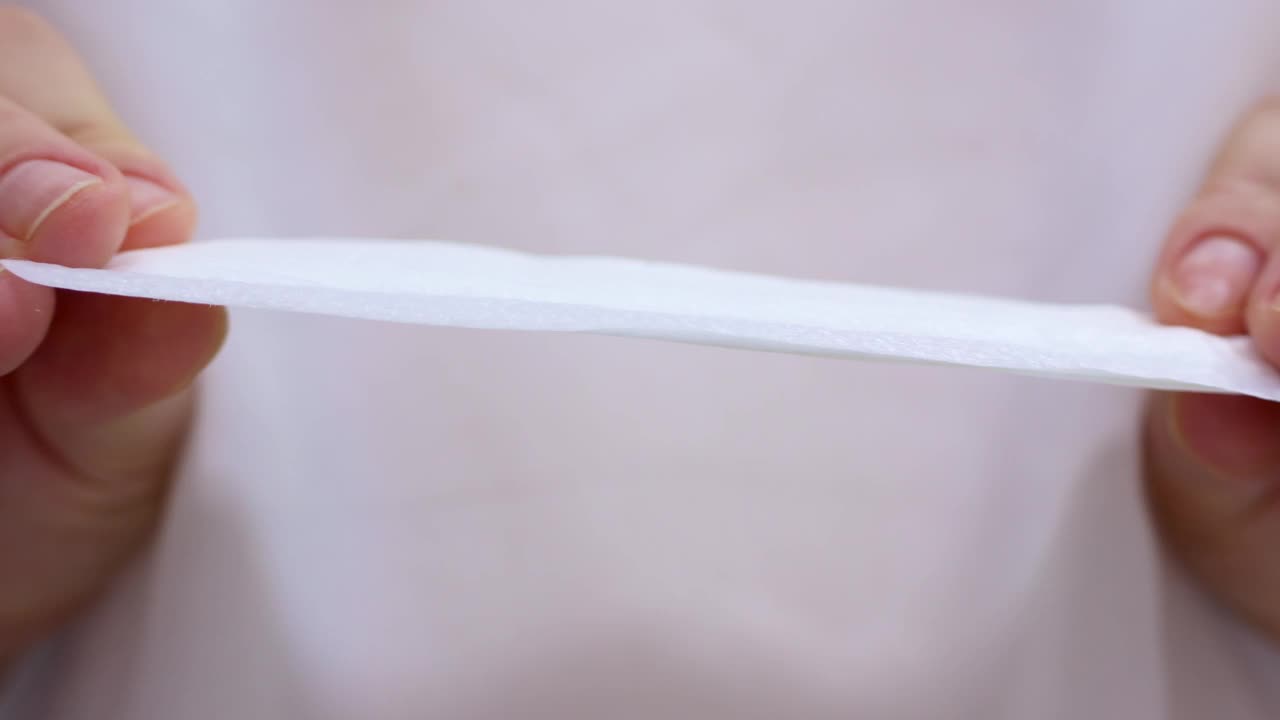 女子双手握着白棉日用卫生巾凑近