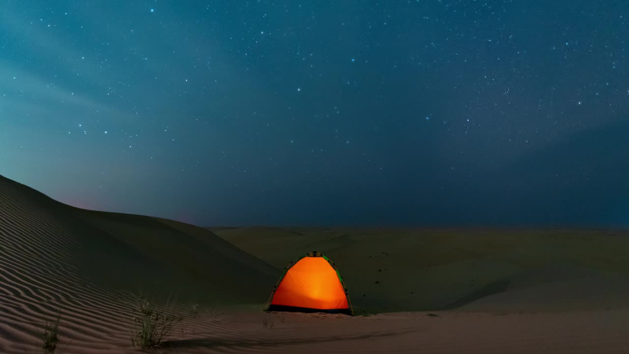 在沙漠野外露营时，星空在夜空中移动。