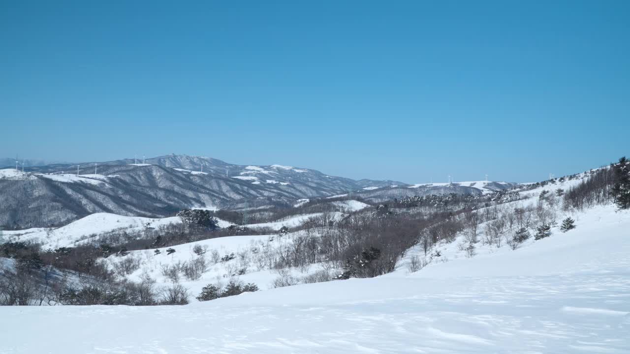 大关岭天空牧场在晴朗晴朗的日子里，在白雪覆盖的山脊上看到风车或风力涡轮机生产绿色能源