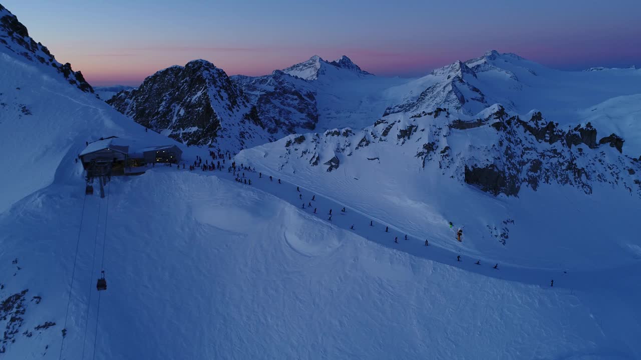 清晨无人机在雪山阿尔卑斯山上空拍摄。意大利阿尔卑斯山风景如画。黎明时分，从空中俯瞰普雷塞纳冰川。滑雪者从斜坡上下来。人们在Presena滑雪。