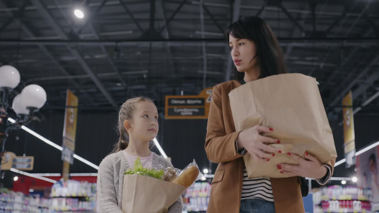 母亲和孩子提着纸袋在超市里购物