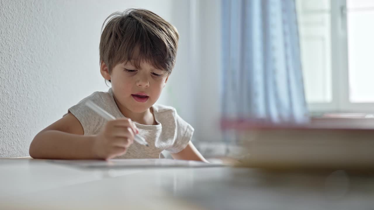 少年坐在书桌前，在房间里练习书法