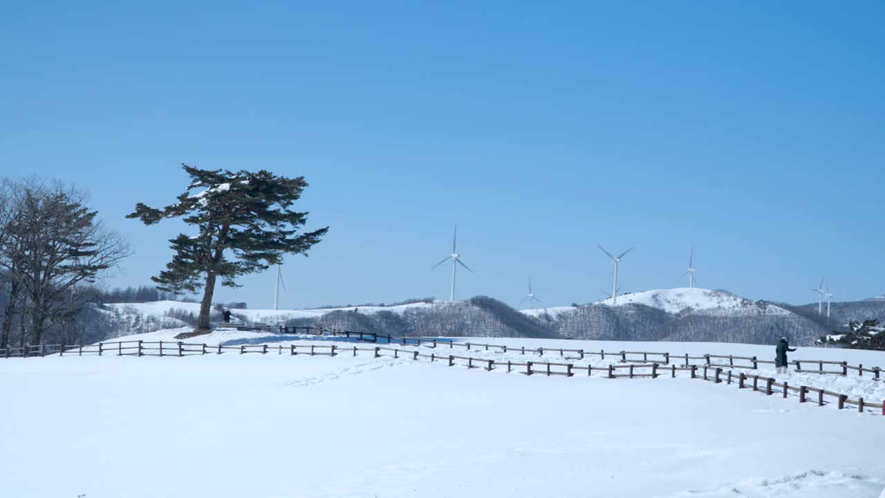 游客们在大关岭天空牧场跑道上用风力涡轮机拍摄壮观的冬季景观