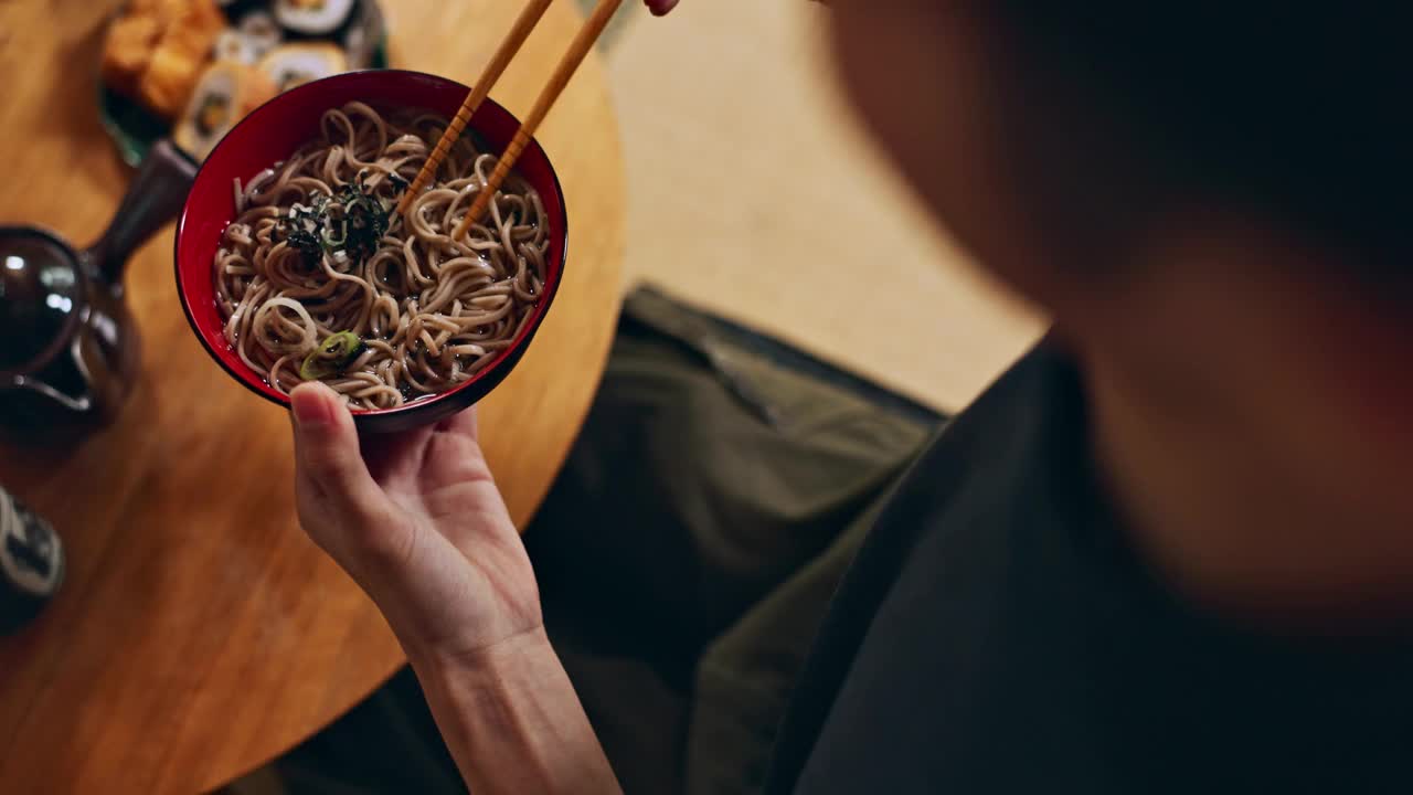 碗面的特写，手和人正在用筷子吃食物，营养和寿司。渴望日本料理，汤和亚洲文化，午餐或晚餐的传统美食