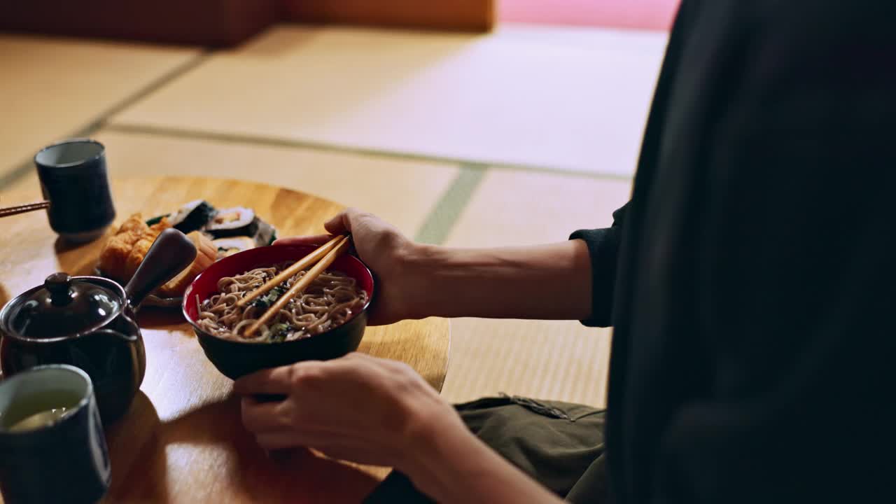 碗面的特写，手和男人正在用筷子吃食物，营养和寿司。午餐或晚餐想吃日本料理、汤和亚洲文化