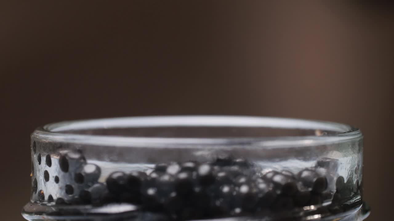 玻璃罐里的黑鱼子酱特写。白鲟在玻璃碗里腌制鱼子。生海鲜。奢华美食。美味可口的鱼制品。质地昂贵的豪华鱼子酱罐头。
