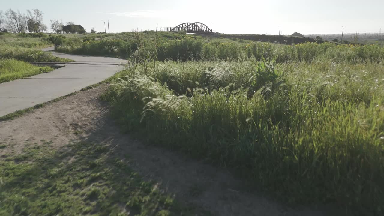 无人机在草地上飞行，狭窄的铁路轨道和穿过公路的钢制人行天桥