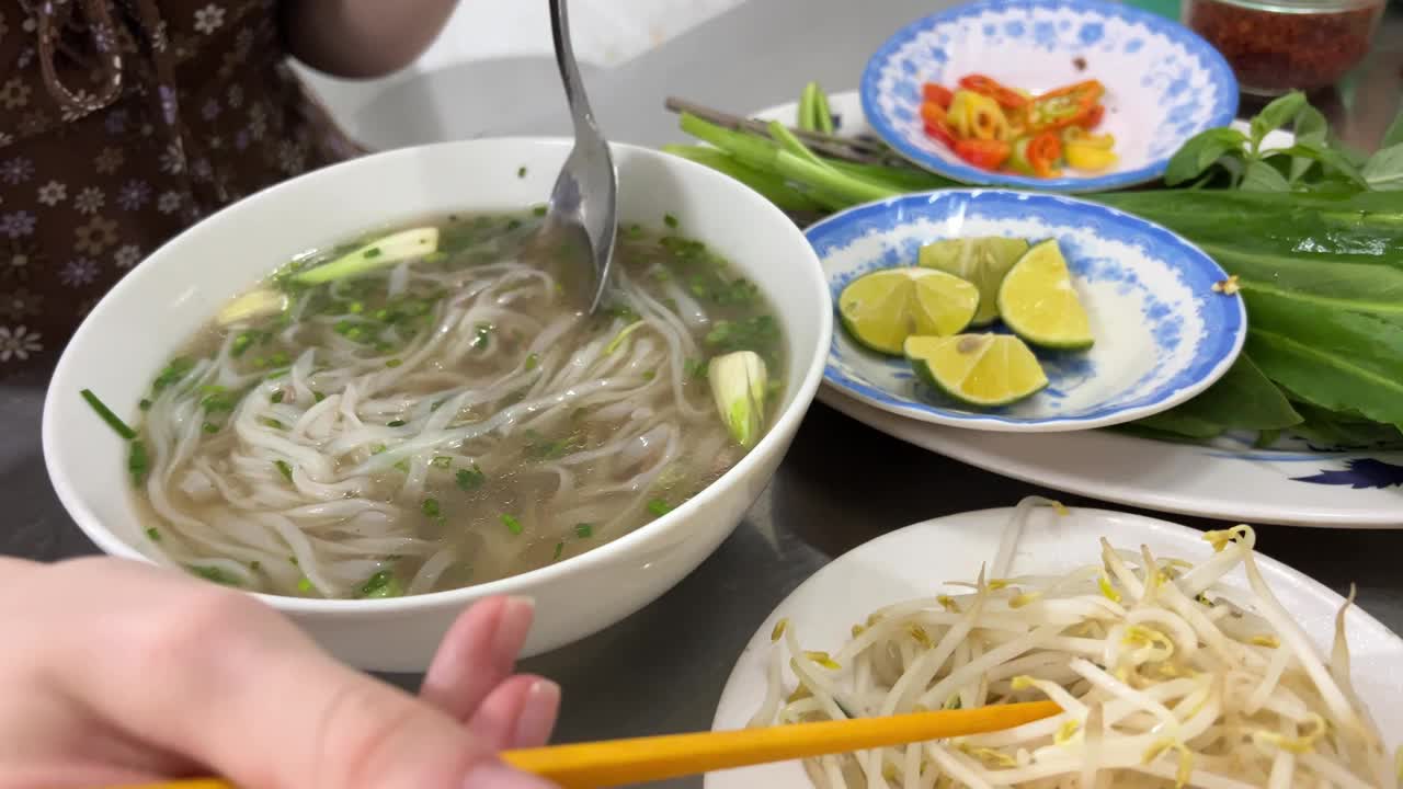 年轻女性在家里用杯子吃面条的特写。垃圾食品概念。