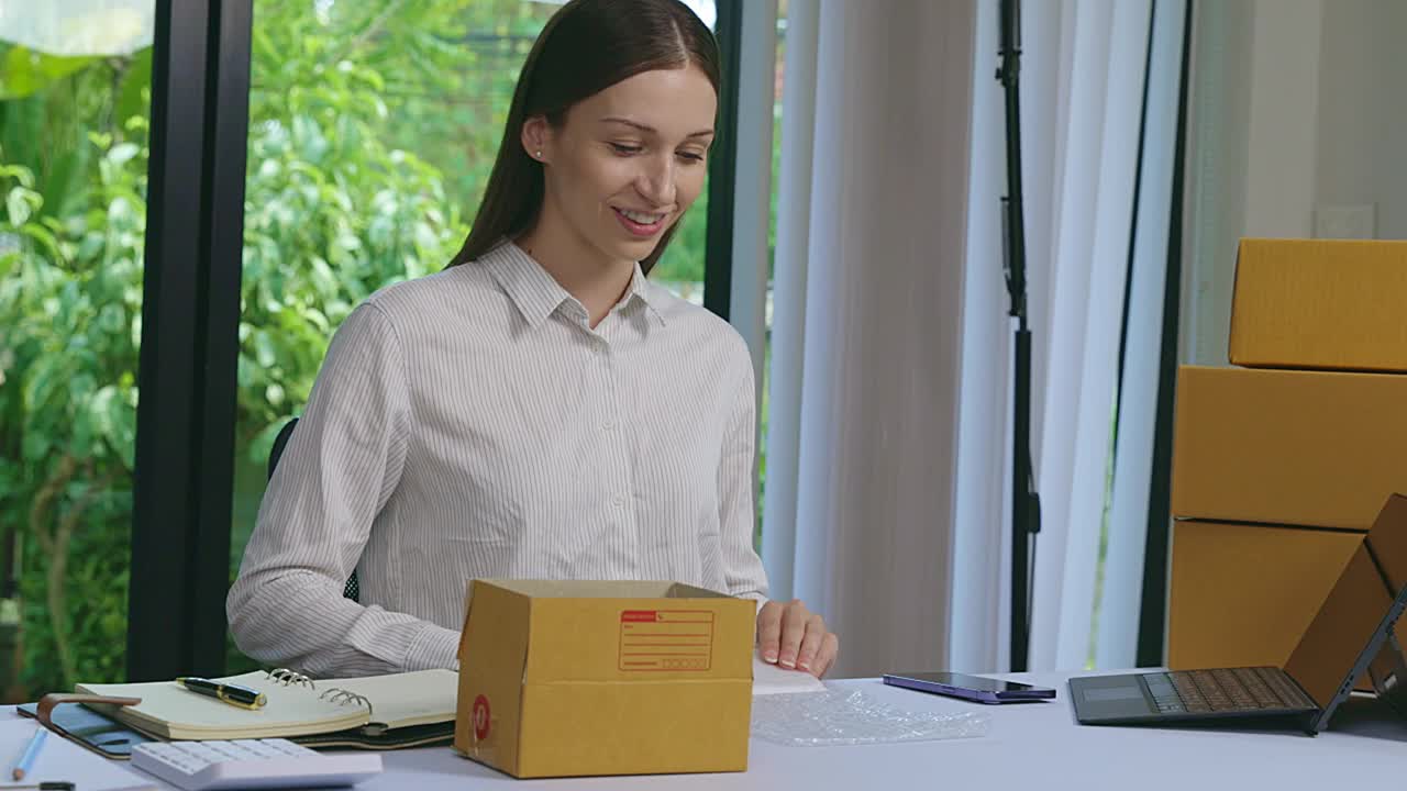 妇女在包装包裹箱。企业主在家包装包裹盒。女士在家里的办公室里准备产品的包裹箱。在线销售和包裹运输。