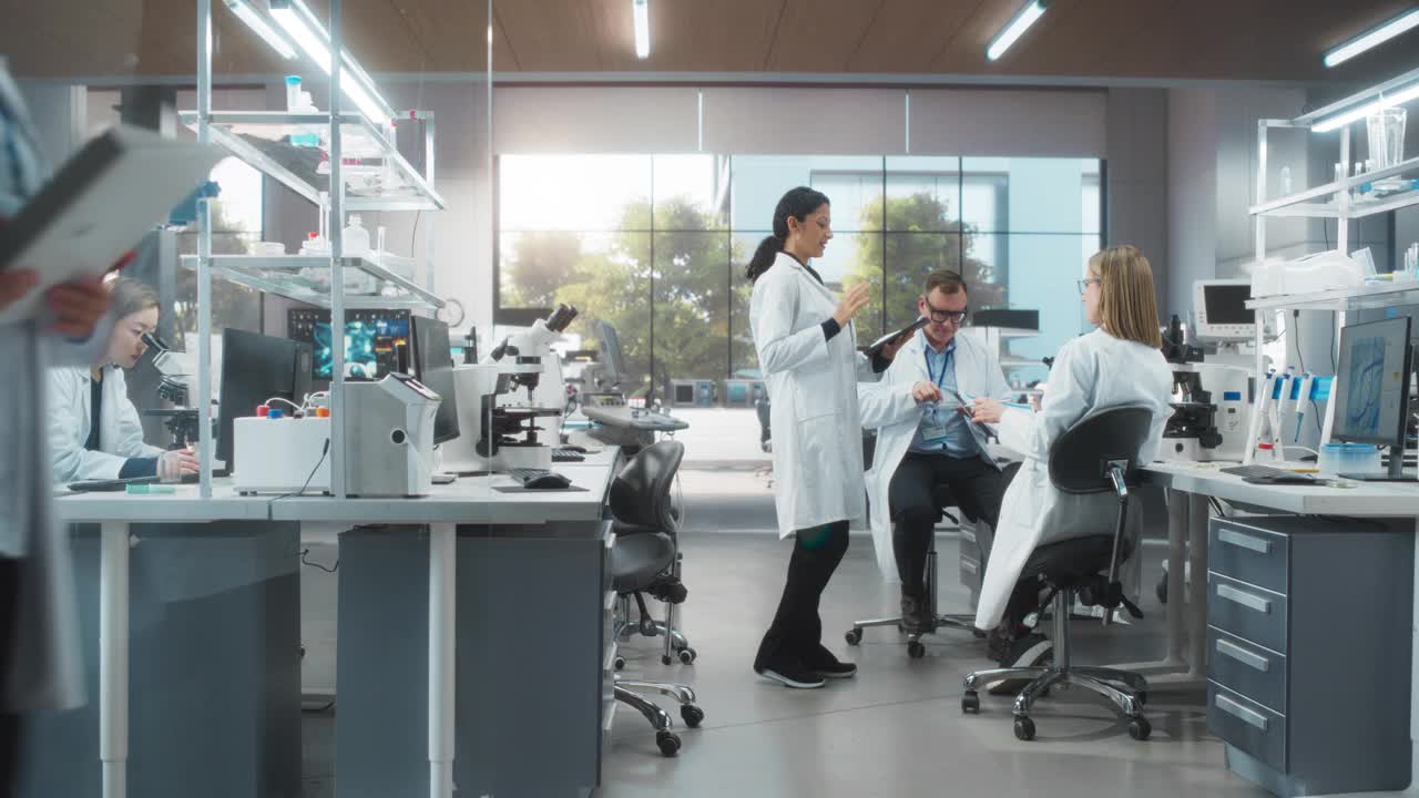 女研究科学家与两位生物工程师就不同药物的作用进行对话。员工在现代科学实验室查看在线报告