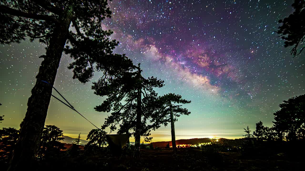 延時拍攝，彩色銀河在山上移動，夜空中的樹帳星