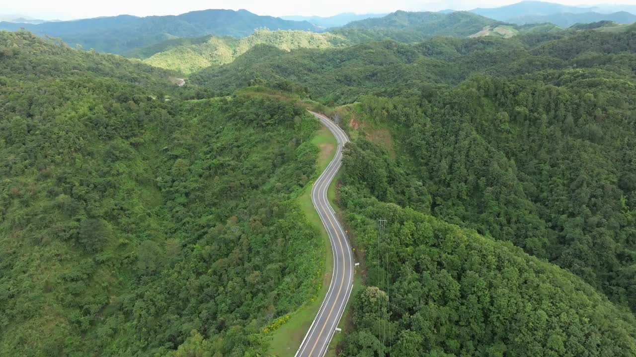 鸟瞰深绿色的森林道路和白色的电动车自然景观和高架道路探险旅行交通和环保理念