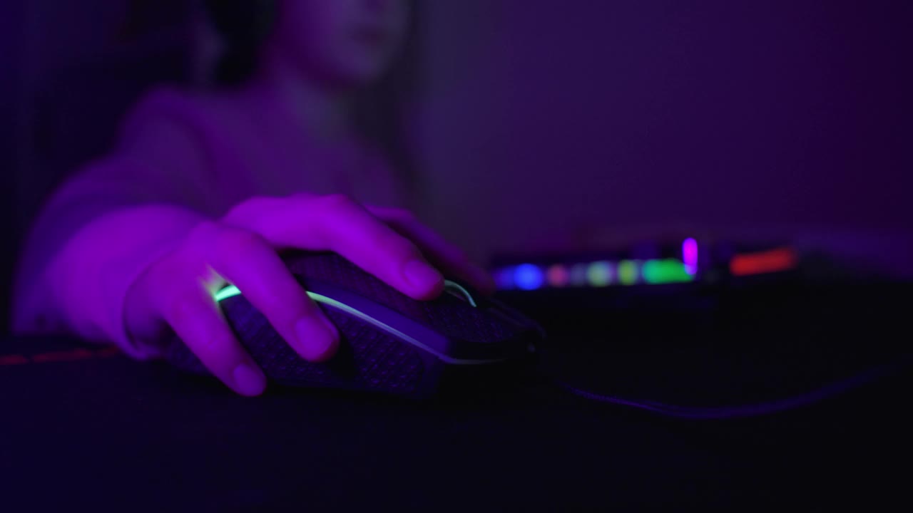 女孩戴着耳机玩电脑游戏。女孩在房间玩电脑游戏，电子竞技游戏，儿童游戏成瘾。孩子在家玩电脑游戏。在线视频游戏技术。