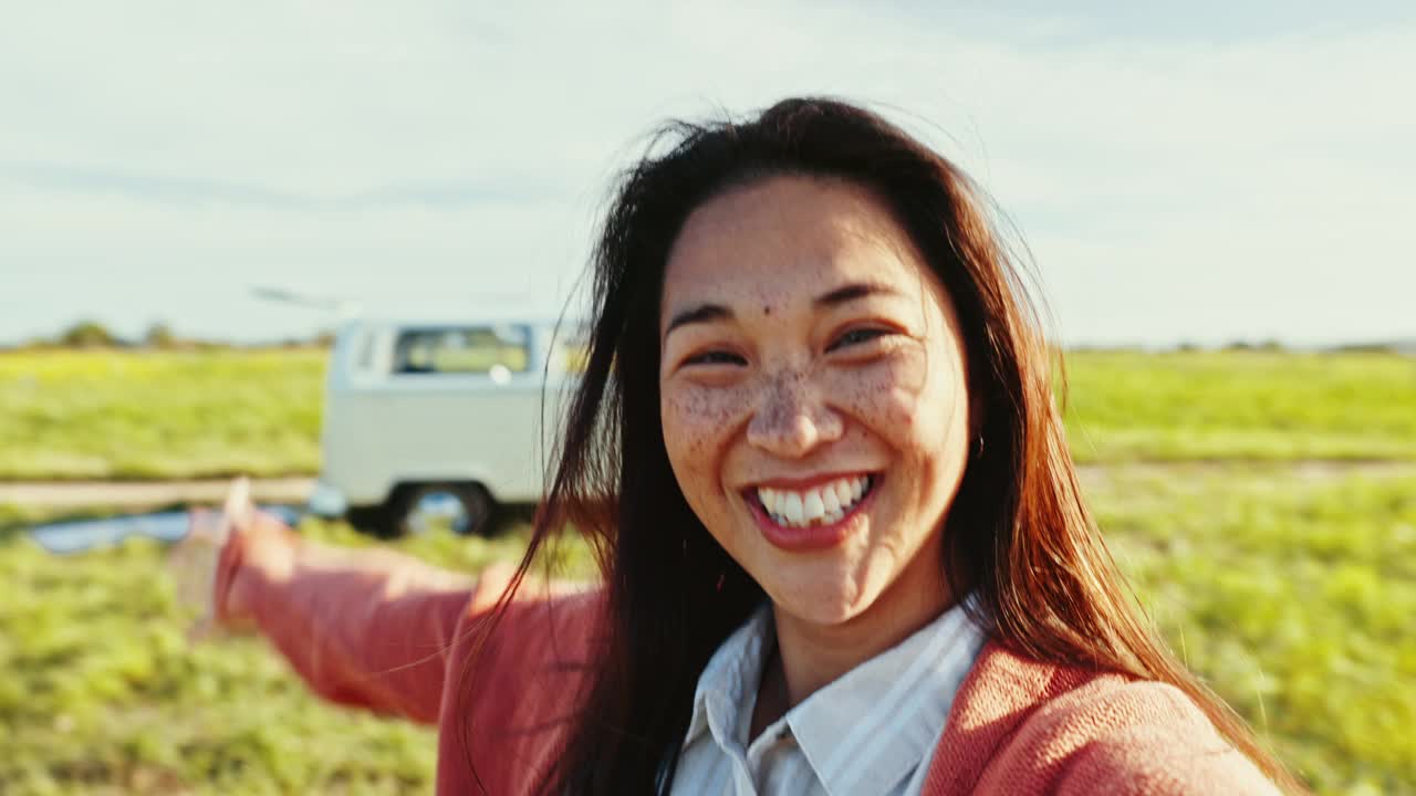 快乐，视频和女人的脸在自然冒险与大篷车在公路旅行的乐趣。微笑，旅行和年轻亚洲女性的肖像，在乡村户外录制视频。