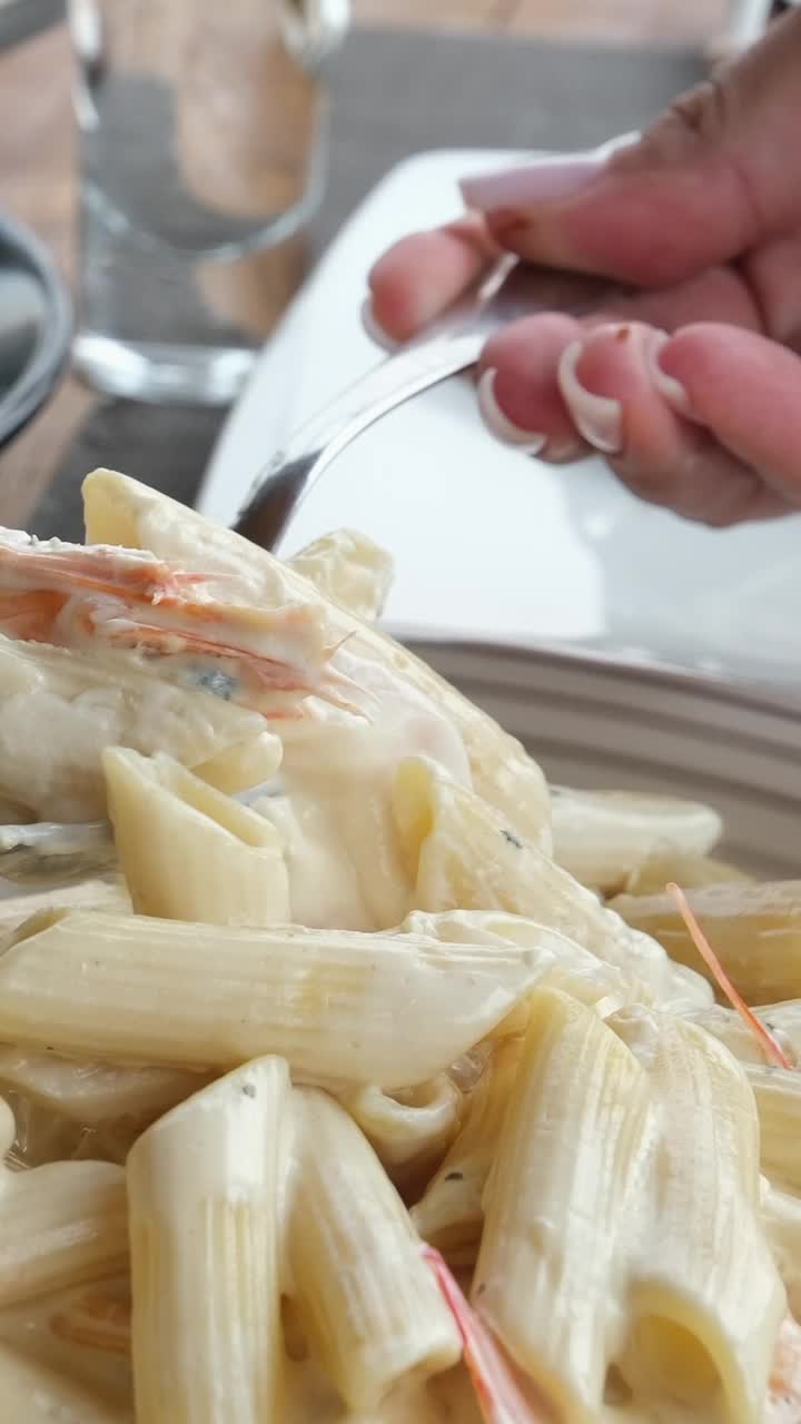 海鲜意面，虾阿尔弗雷多意面食谱。厨师在煮熟的意大利面上浇奶油酱，在意大利面里加奶酪，用叉子搅拌均匀