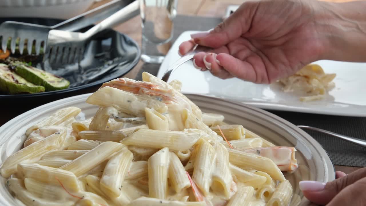 海鲜意面，虾阿尔弗雷多意面食谱。厨师在煮熟的意大利面上浇奶油酱，在意大利面里加奶酪，用叉子搅拌均匀