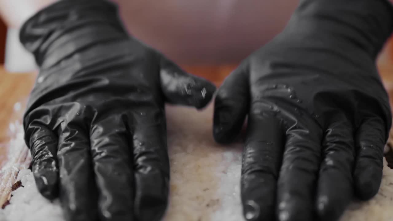 厨师正在用米饭和海苔制作寿司卷。日本厨师做寿司的双手