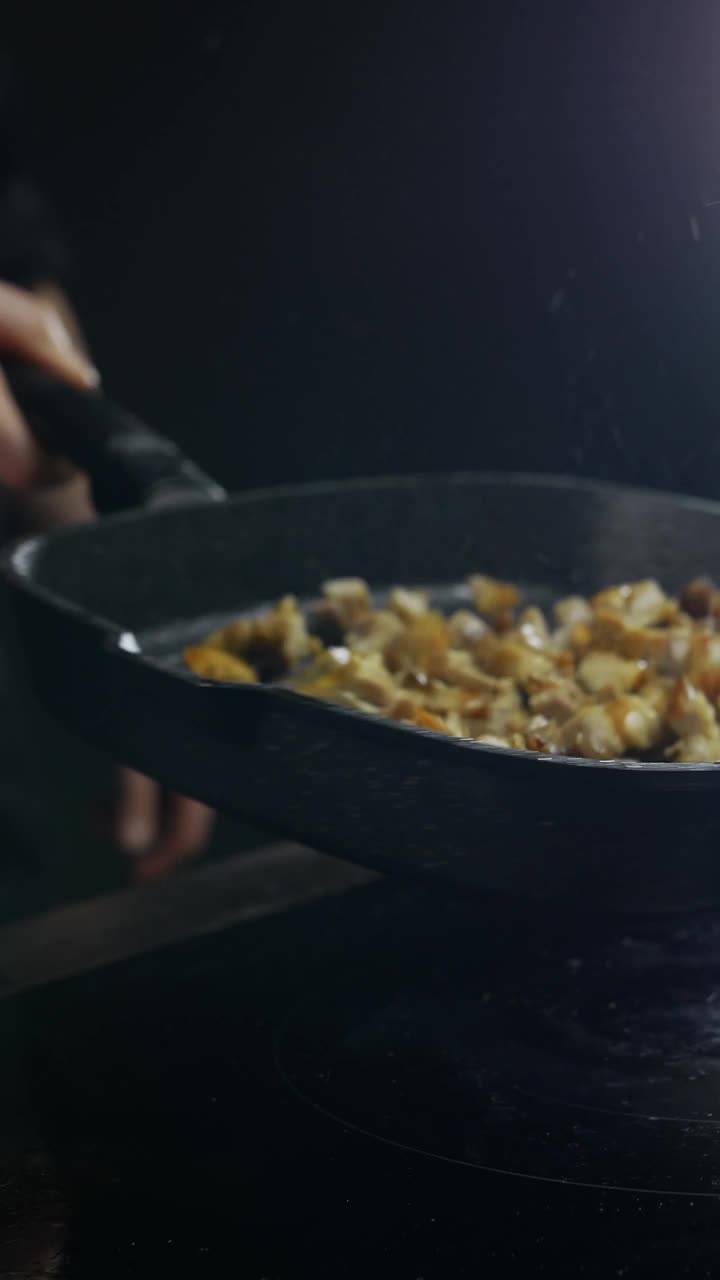 厨师用精准的手部动作熟练地将鸡肉放入锅中。