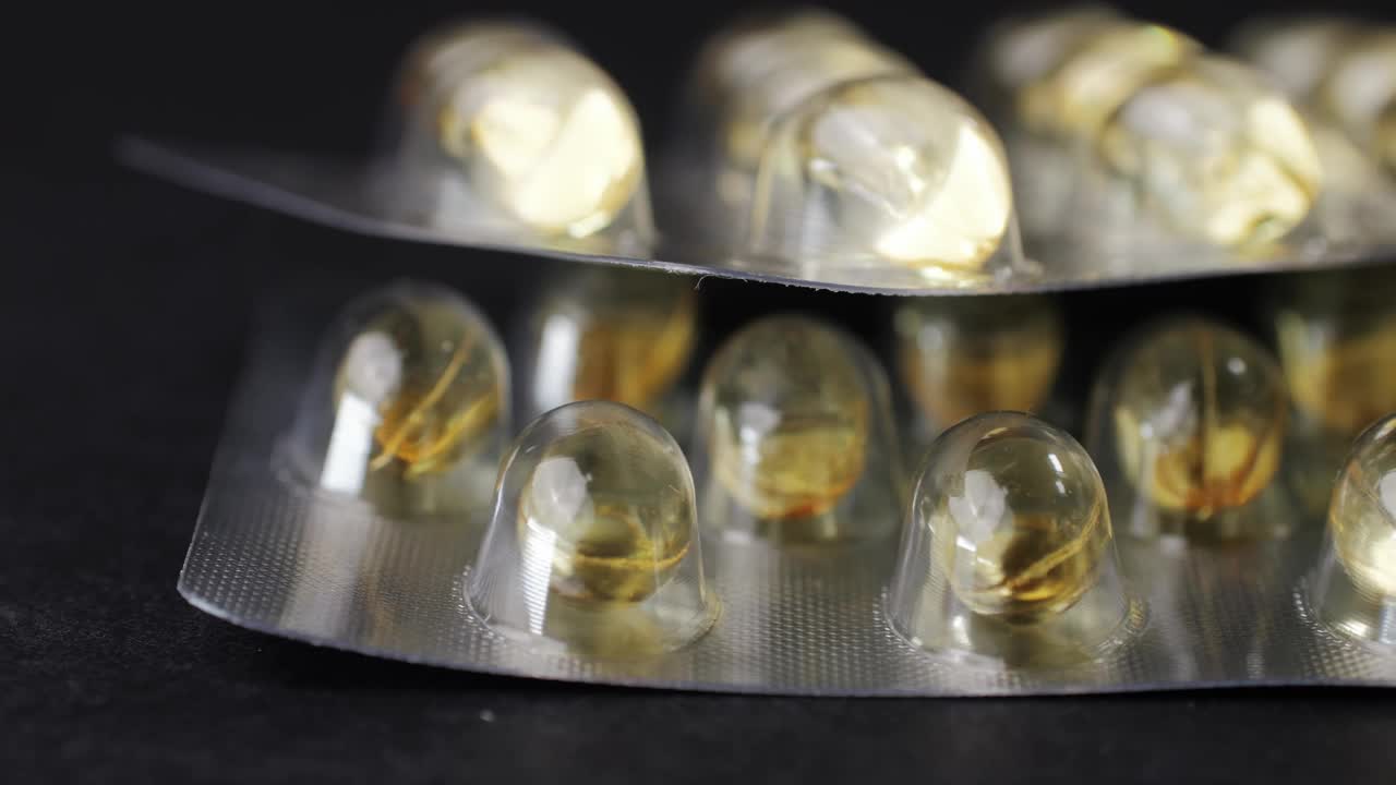 包裹欧米茄鱼油凝胶胶囊黑色背景特写。欧米茄维生素丸3 6 9。要健康，保重身体。制药行业。生物补充剂业务