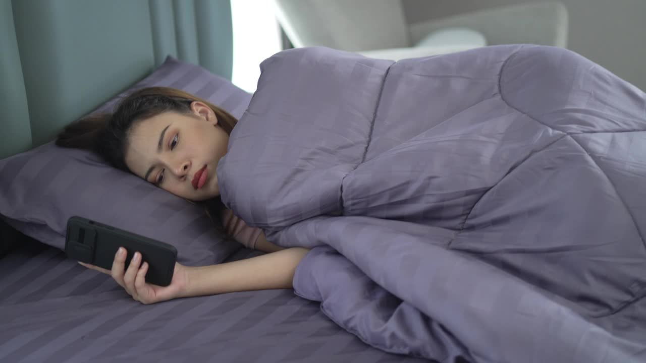 漂亮女人醒来后玩她的智能手机。
