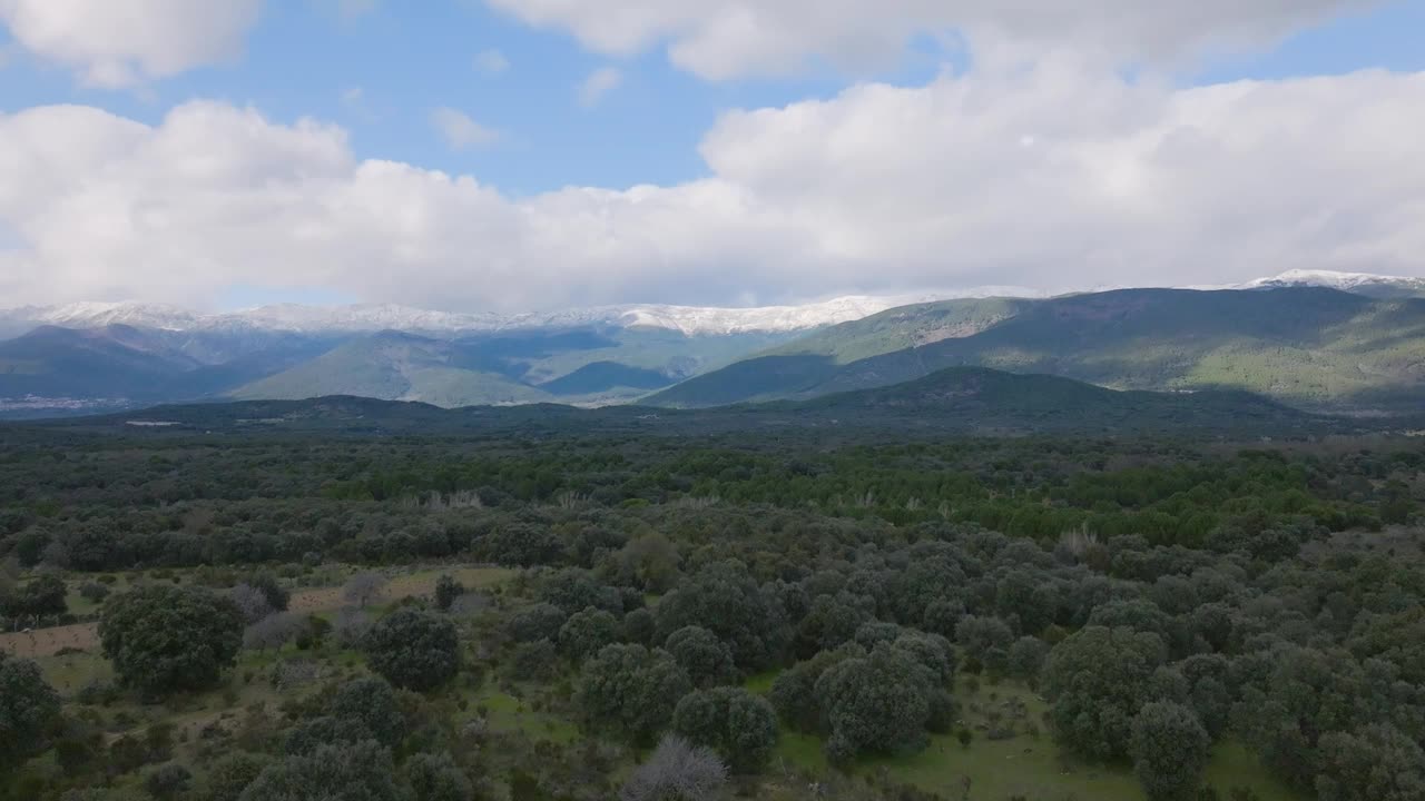我和一架无人机在格雷多斯山脉，白雪皑皑的山峰，乌云密布的天空和平原上，一片森林和索蒂略德拉阿德拉达镇，那里有一片没有叶子的白杨林，阿维拉，西班牙。