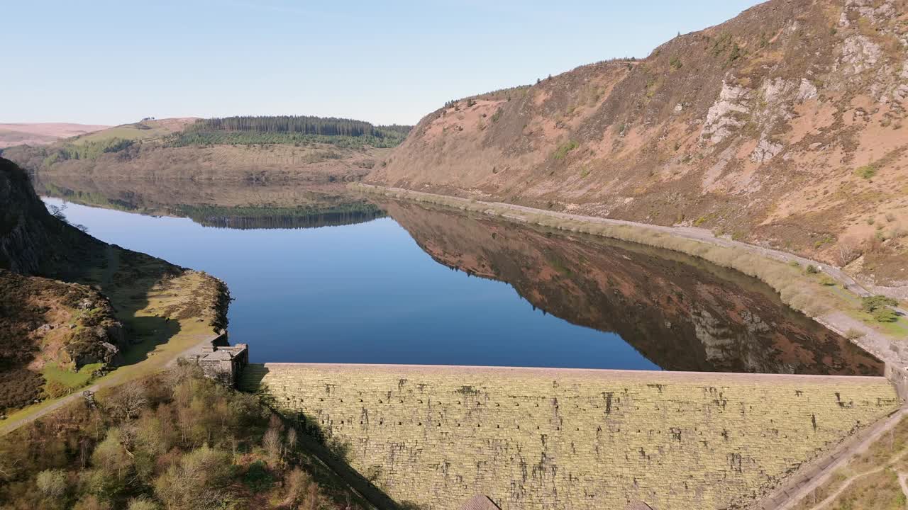 一个阳光明媚的春日，在威尔士波伊斯的伊兰山谷，鸟瞰卡班科赫大坝和水库。从水库飞过大坝